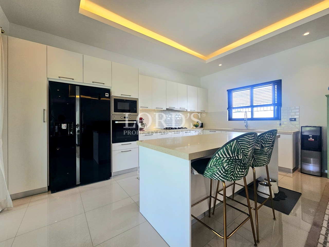 Modern white kitchen with large island, bar stools, and built-in appliances