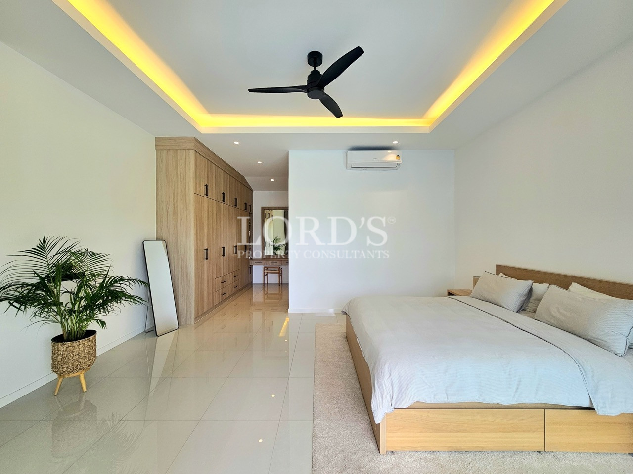 Modern bedroom with king-size bed, built-in wardrobe, ceiling fan, and air conditioner
