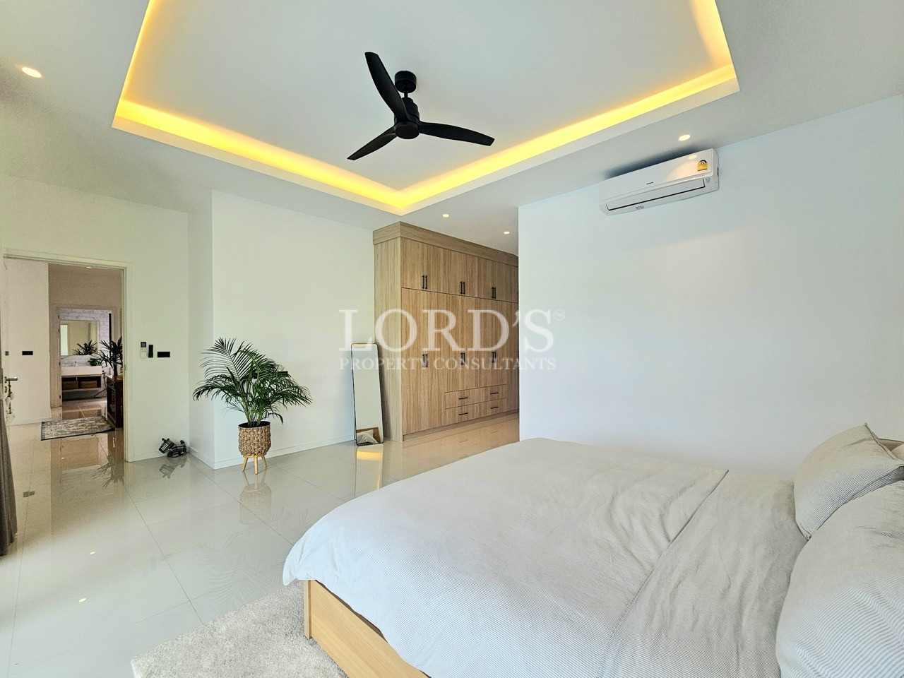 Modern bedroom with king bed, built-in wardrobe, ceiling fan, and air conditioning