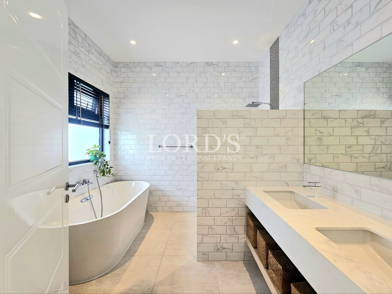 Modern white tiled bathroom with freestanding bathtub, walk-in shower, and double vanity