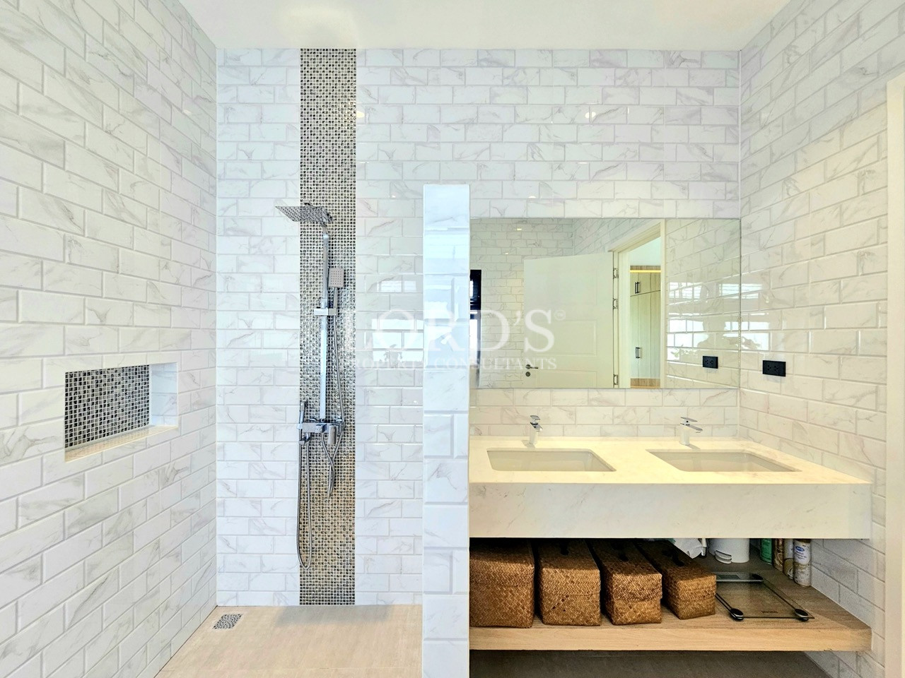 Modern white tiled bathroom with walk-in shower, dual vanity, and large mirror