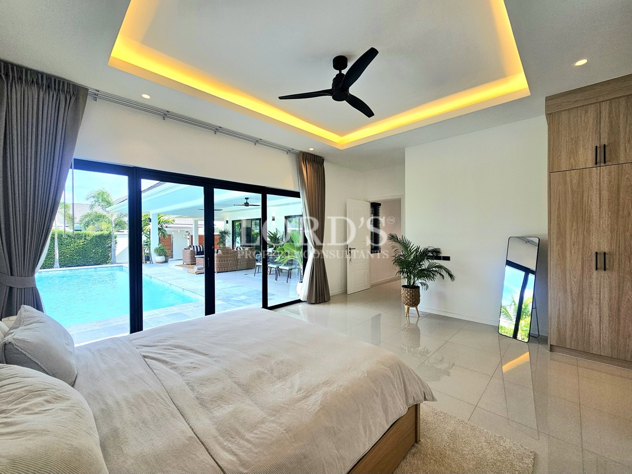 Modern luxury bedroom with pool view, floor-to-ceiling windows, and built-in wardrobe