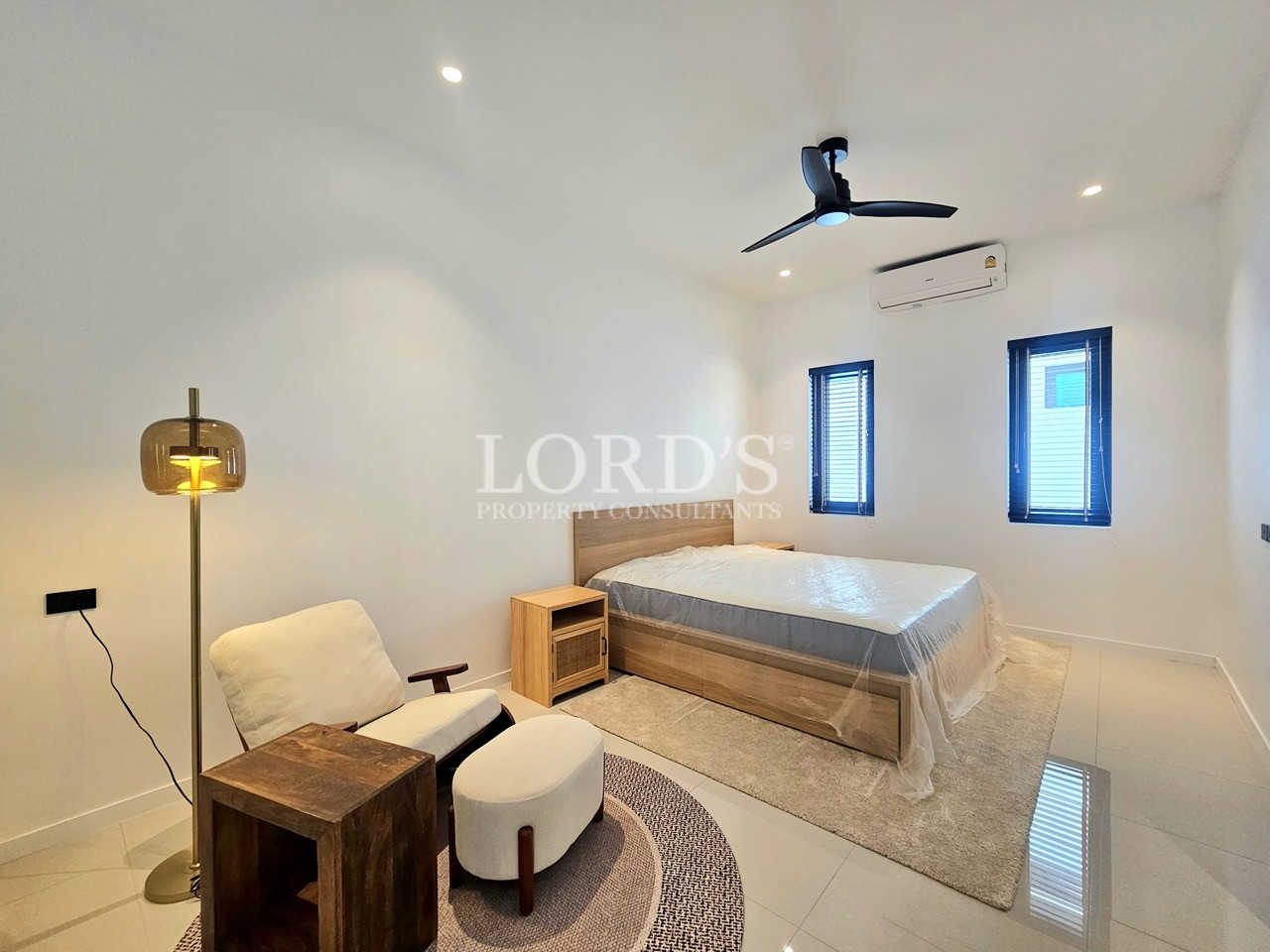 Modern bedroom with king-size bed, lounge chair, and ceiling fan