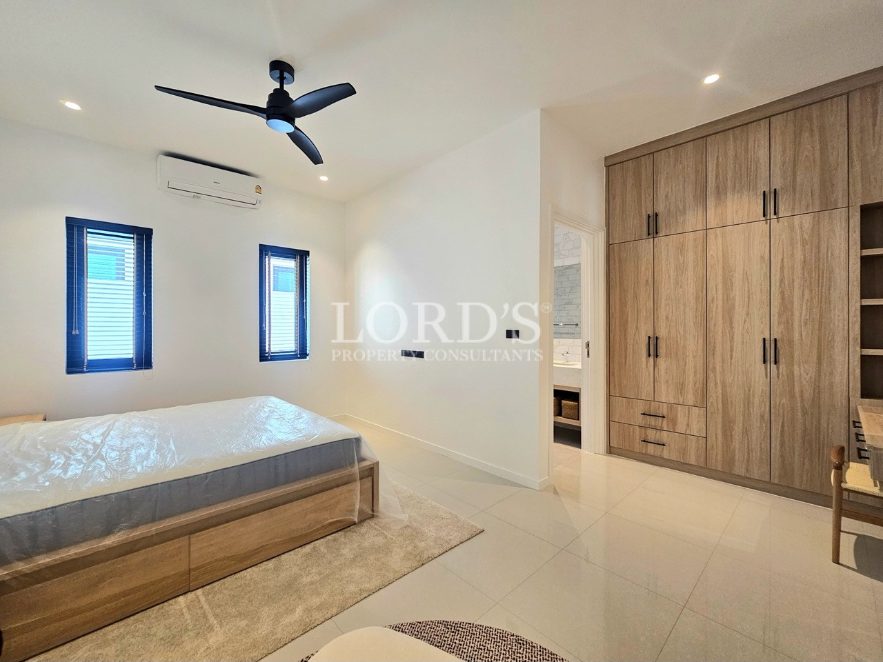 Modern bedroom with wooden bed frame, built-in wardrobe, and ceiling fan