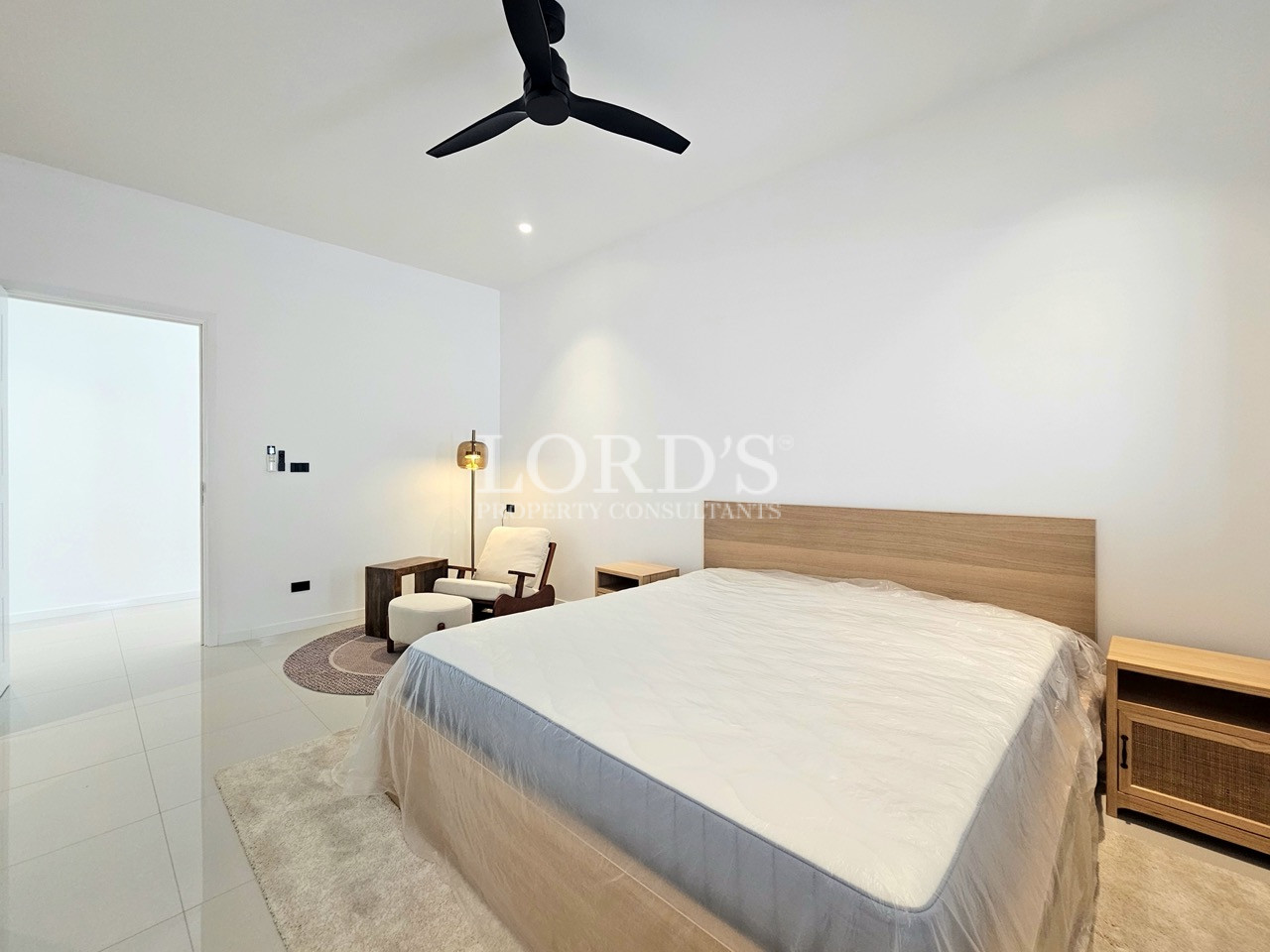 Modern bedroom with king-size bed, wooden headboard, and cozy seating area