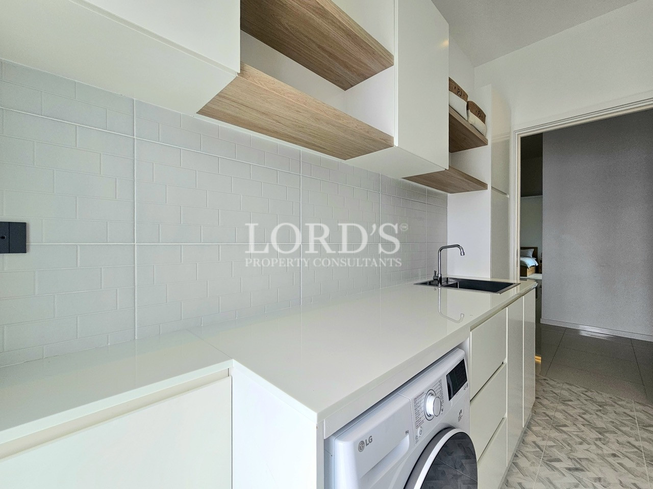 Modern utility room with white countertop, sink, and washing machine