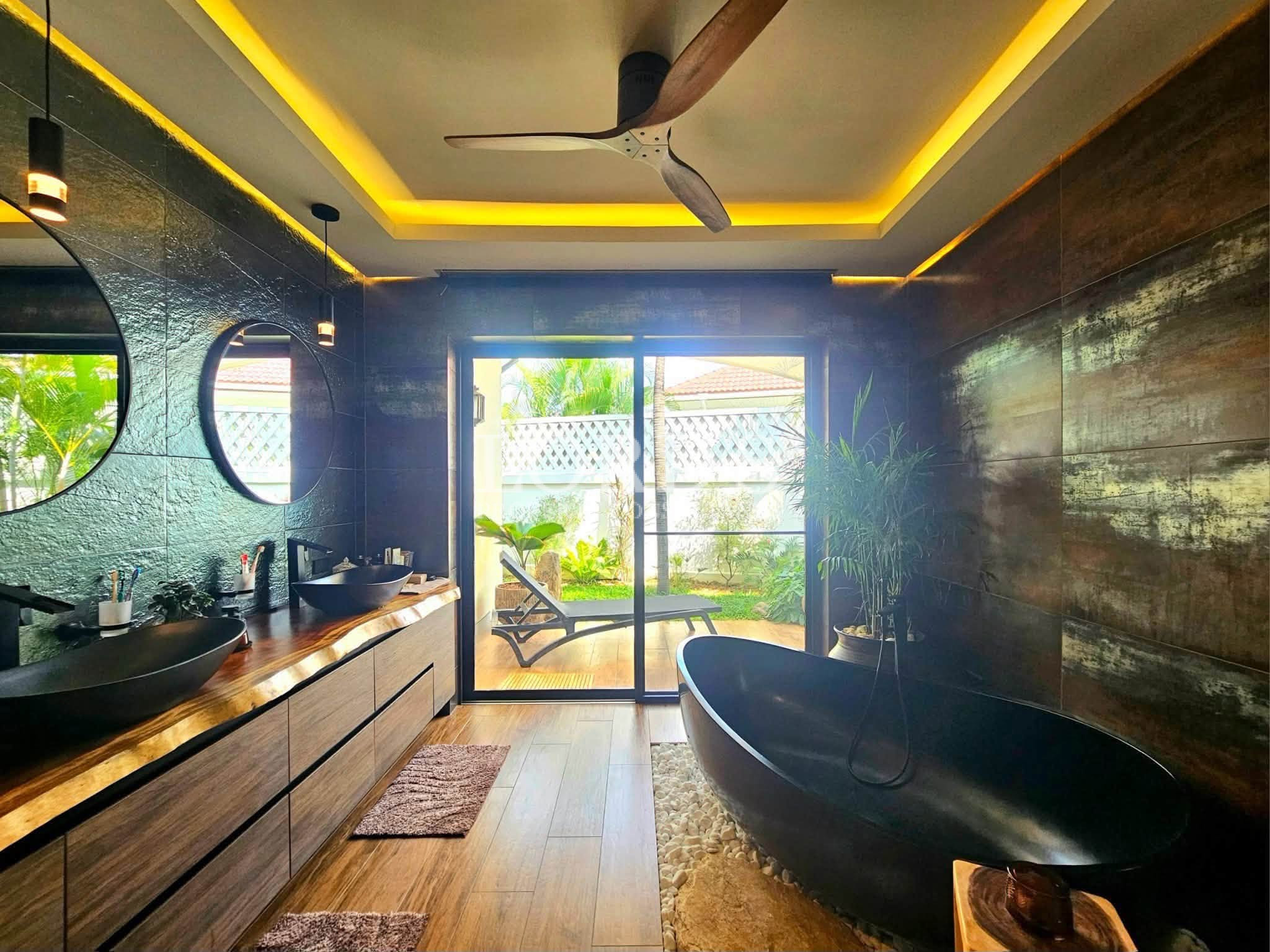 Luxury spa bathroom with freestanding soaking tub, double vanity, round mirrors, and private garden view