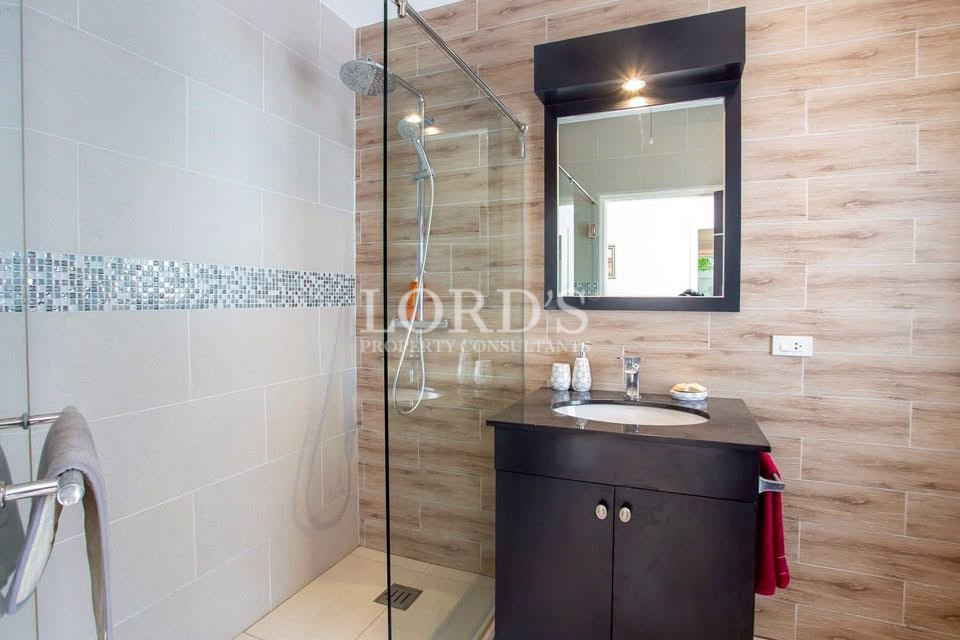 Modern bathroom with a glass-enclosed walk-in shower, rainfall showerhead, vanity, and large mirror