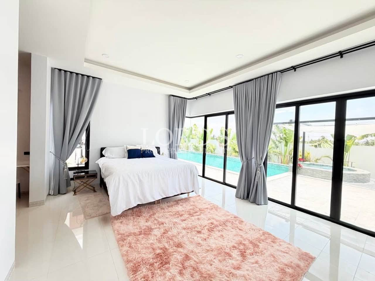 Bright modern bedroom with a king-size bed, gray curtains, and pool views