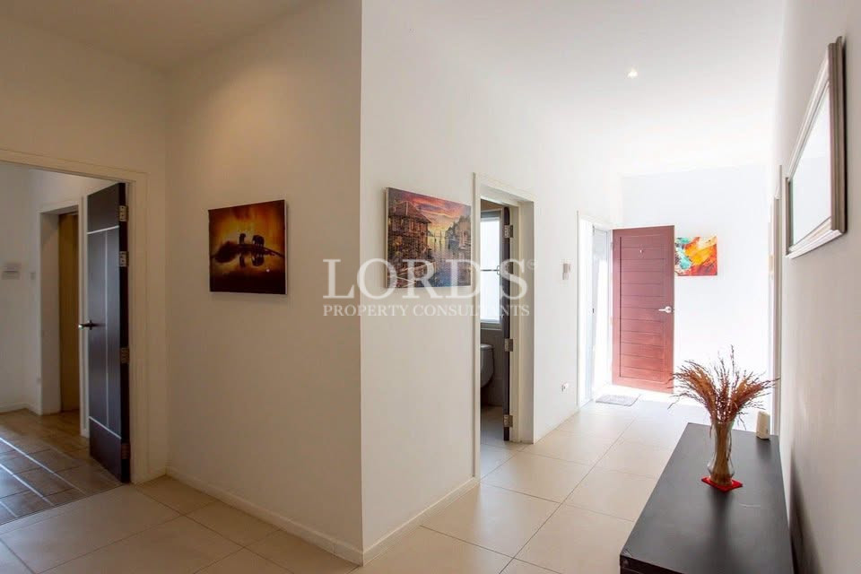 Bright hallway with tiled flooring, wall art, console table, and multiple interior doors