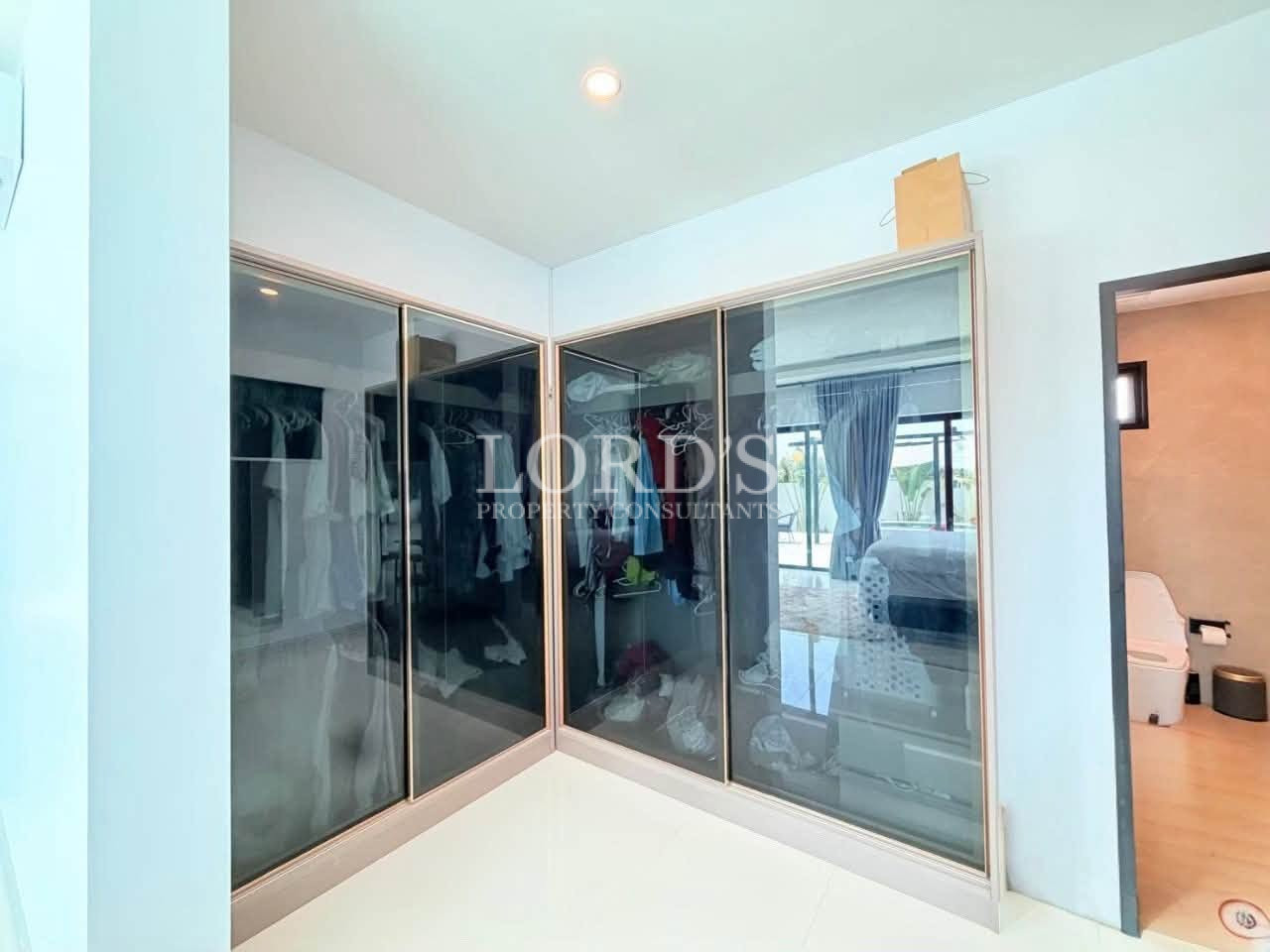 Modern walk-in wardrobe with tinted glass sliding doors and built-in storage