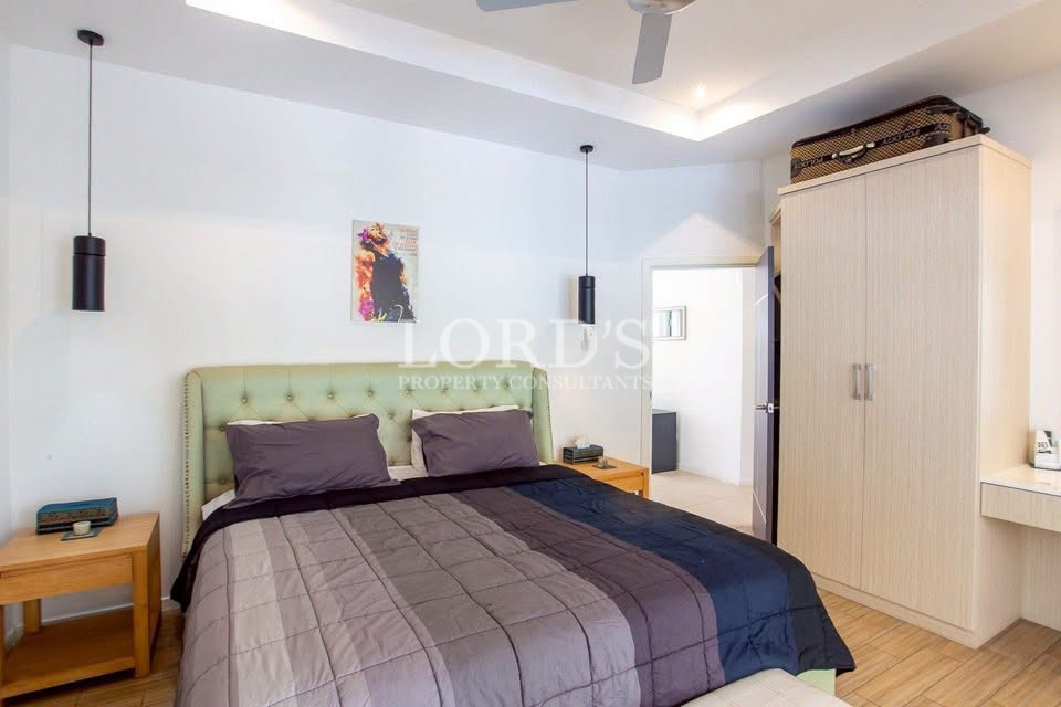 Bright bedroom with upholstered bed, bedside tables, pendant lights, and built-in wardrobe