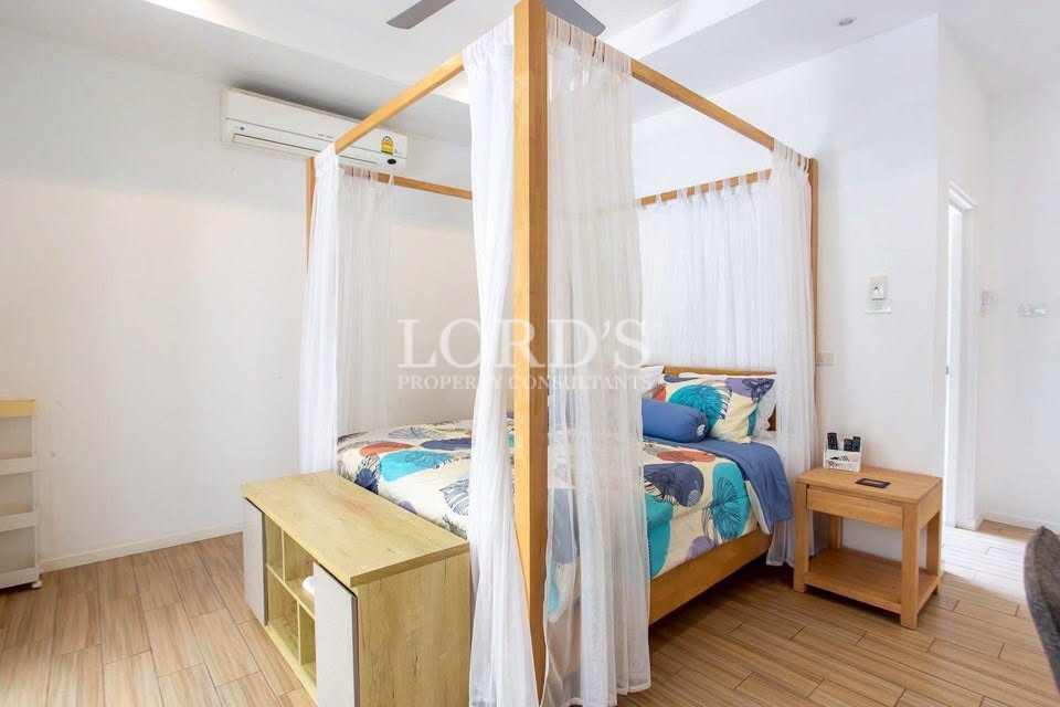 Bright four-poster bedroom with sheer curtains, colorful bedding, and air conditioning