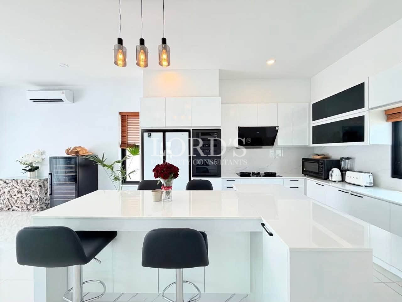 Modern white kitchen with large island and black bar stools