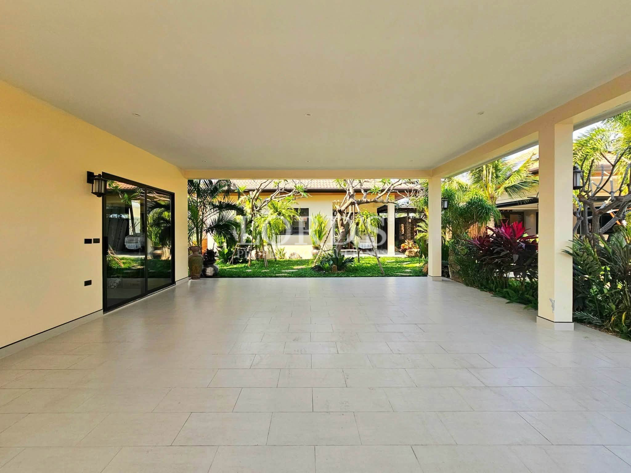 Spacious covered outdoor patio with landscaped courtyard, sliding glass doors, and tropical garden views