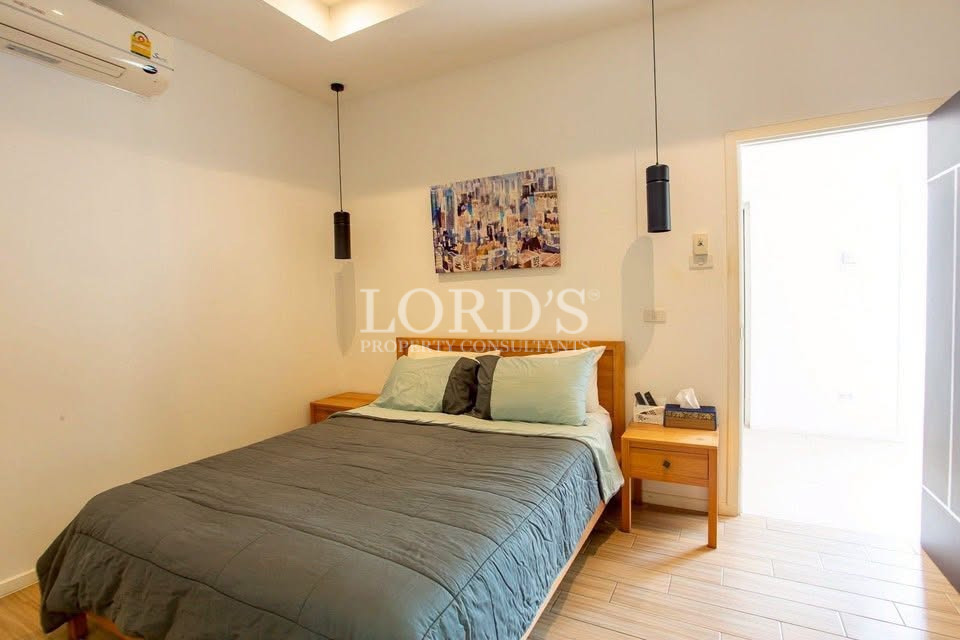 Bright bedroom with double bed, bedside tables, pendant lights, and air conditioning