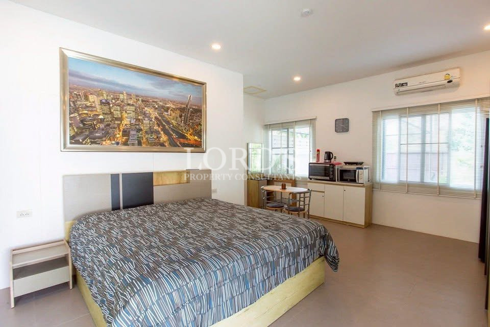 Spacious bedroom with king-size bed, cityscape artwork, kitchenette, and air conditioning