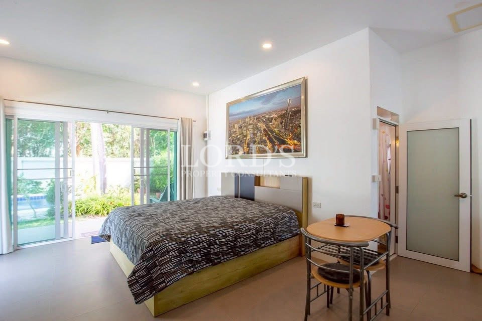 Bright bedroom with king-size bed, garden view, and sliding glass doors