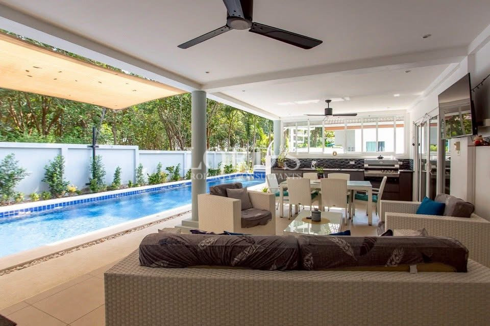 Covered outdoor living and dining area beside a private swimming pool