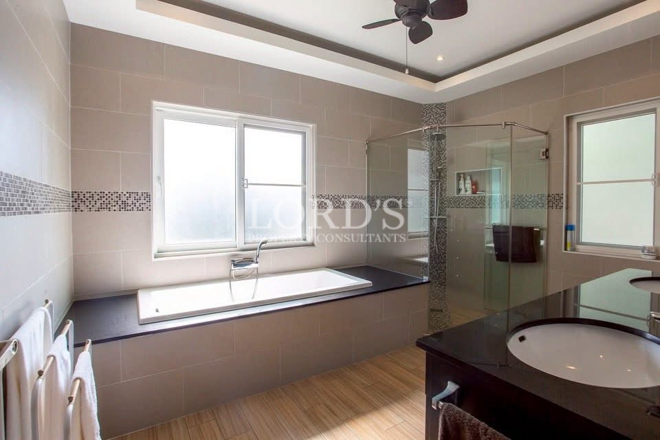 Modern bathroom with bathtub, glass-enclosed shower, double vanity, and large windows