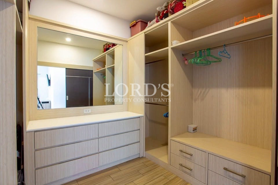 Built-in walk-in wardrobe with drawers, hanging space, shelving, and dressing mirror