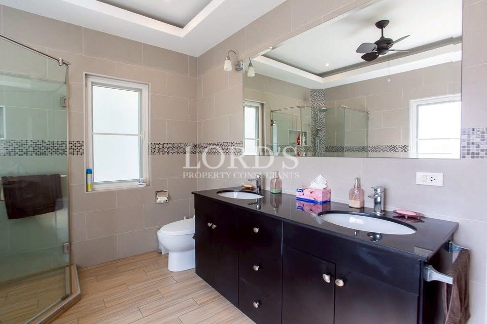 Modern bathroom with double vanity, glass shower enclosure, large mirror, and ceiling fan
