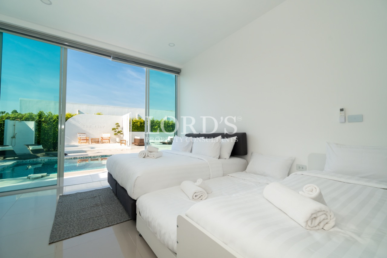 Modern bedroom with two beds overlooking a private swimming pool
