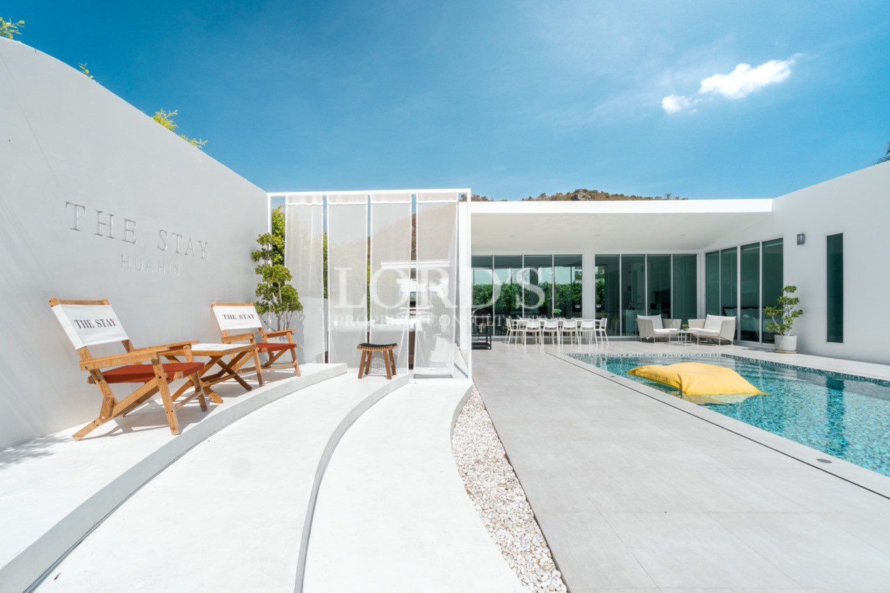 Modern private villa with swimming pool, outdoor seating, and glass doors