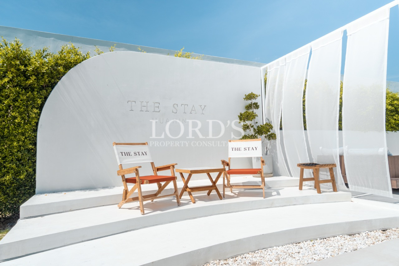 Modern outdoor seating area with wooden chairs and white architectural walls