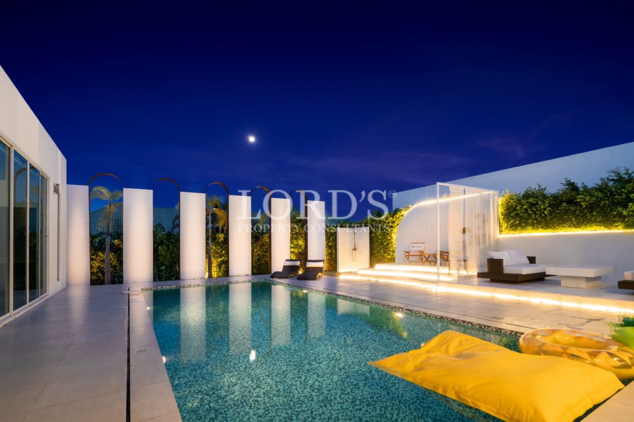 Luxury modern villa pool at night with illuminated outdoor seating and moonlit sky