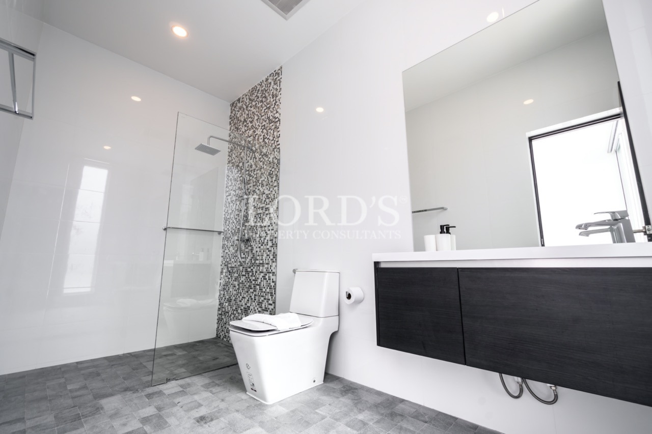 Modern white bathroom with walk-in shower, toilet, and black vanity