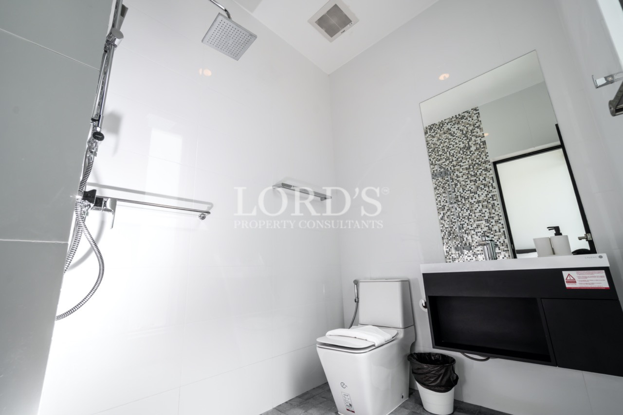 Modern white bathroom with walk-in shower, toilet, and black vanity