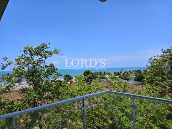 Private balcony with ocean view overlooking lush tropical greenery and the coastline from a modern apartment
