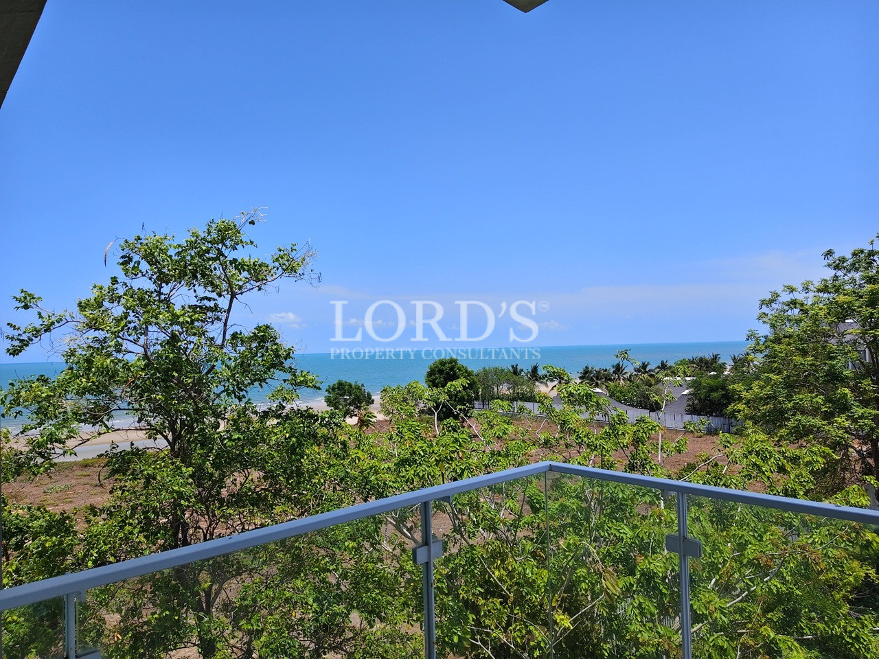 Private balcony with ocean view overlooking lush tropical greenery and the coastline from a modern apartment