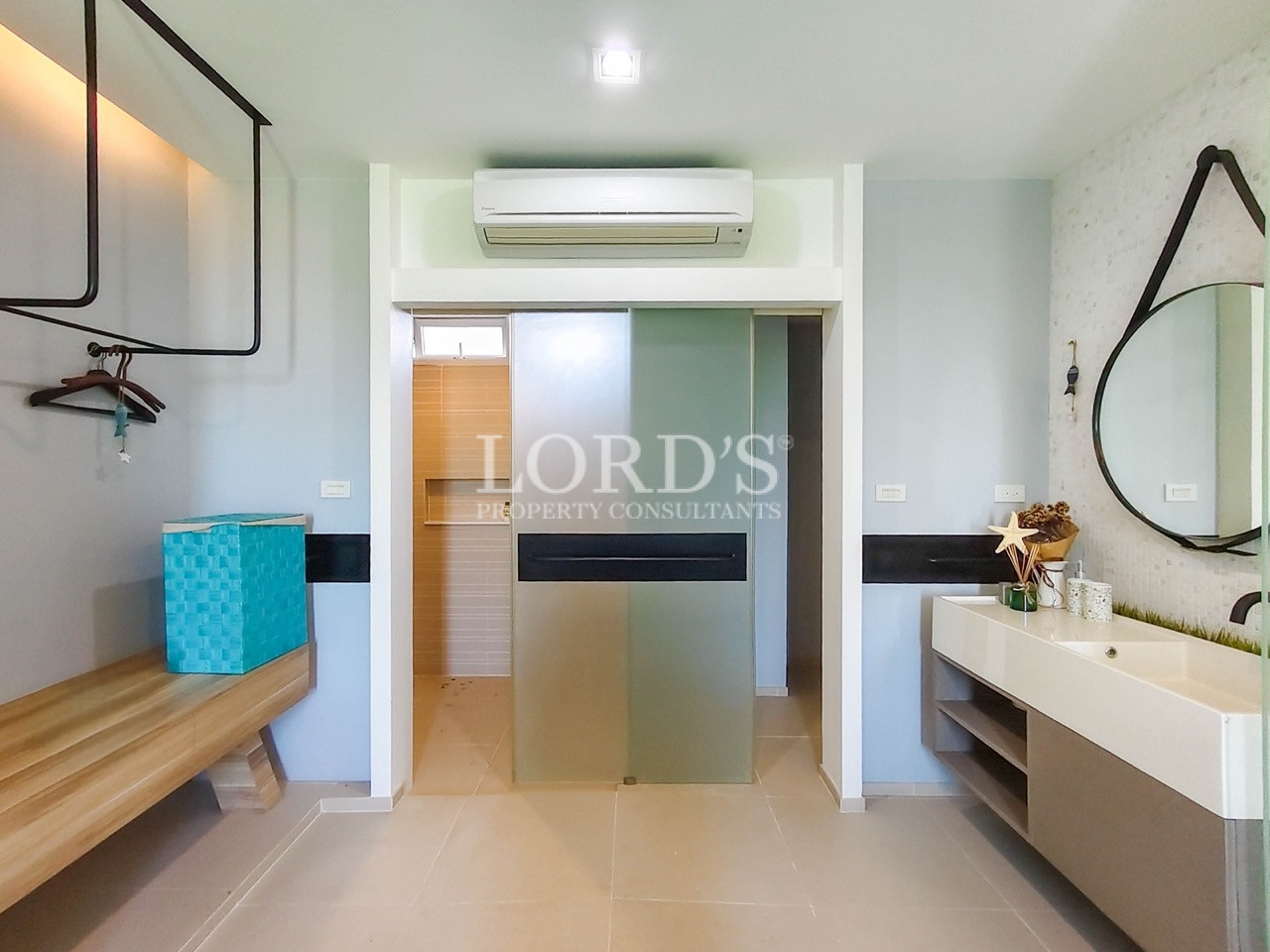 Modern apartment vanity area with floating sink, open wardrobe, sliding glass door, and contemporary interior design