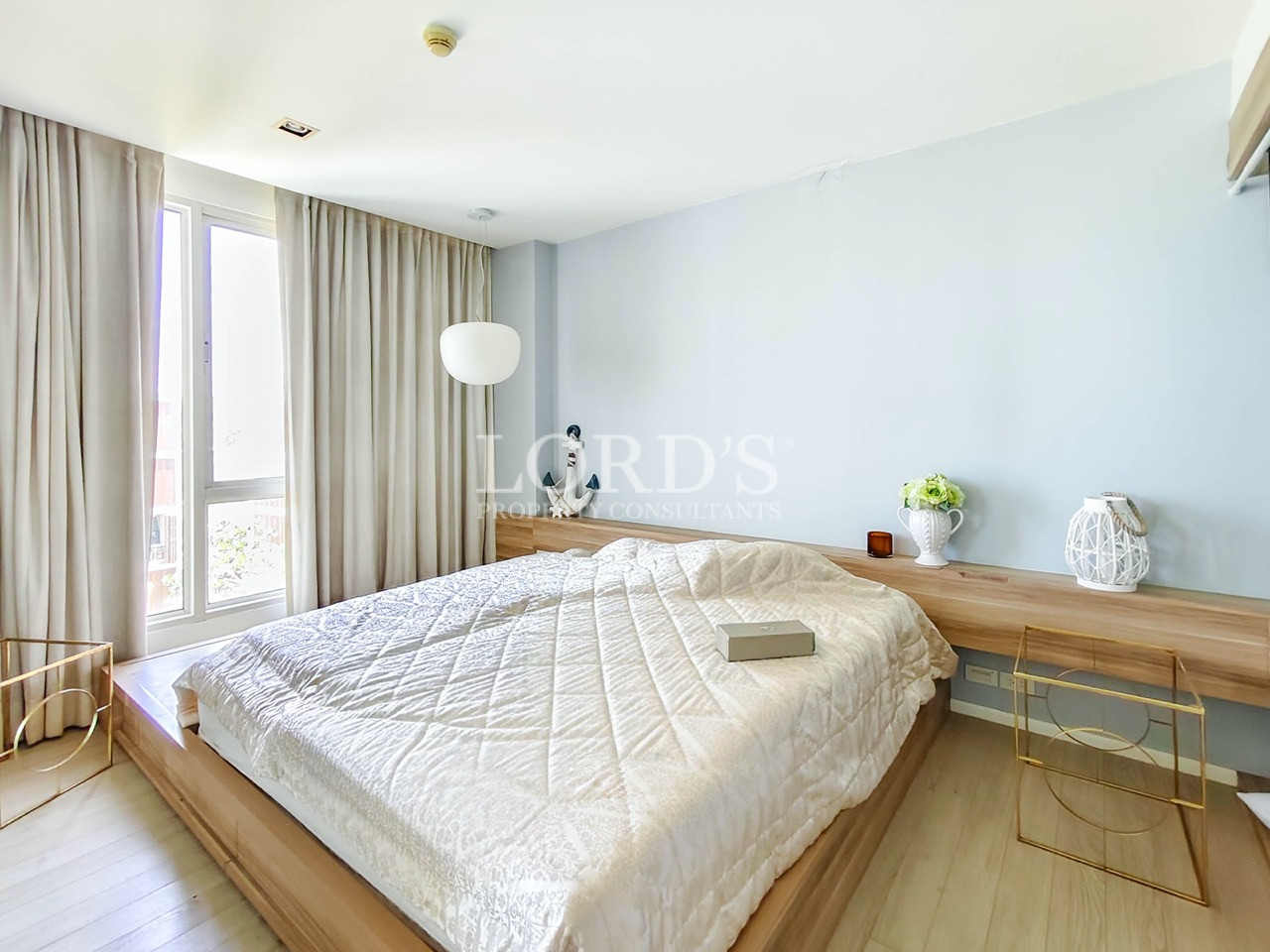 Modern apartment bedroom with large windows, wooden platform bed, built-in desk, and contemporary interior design