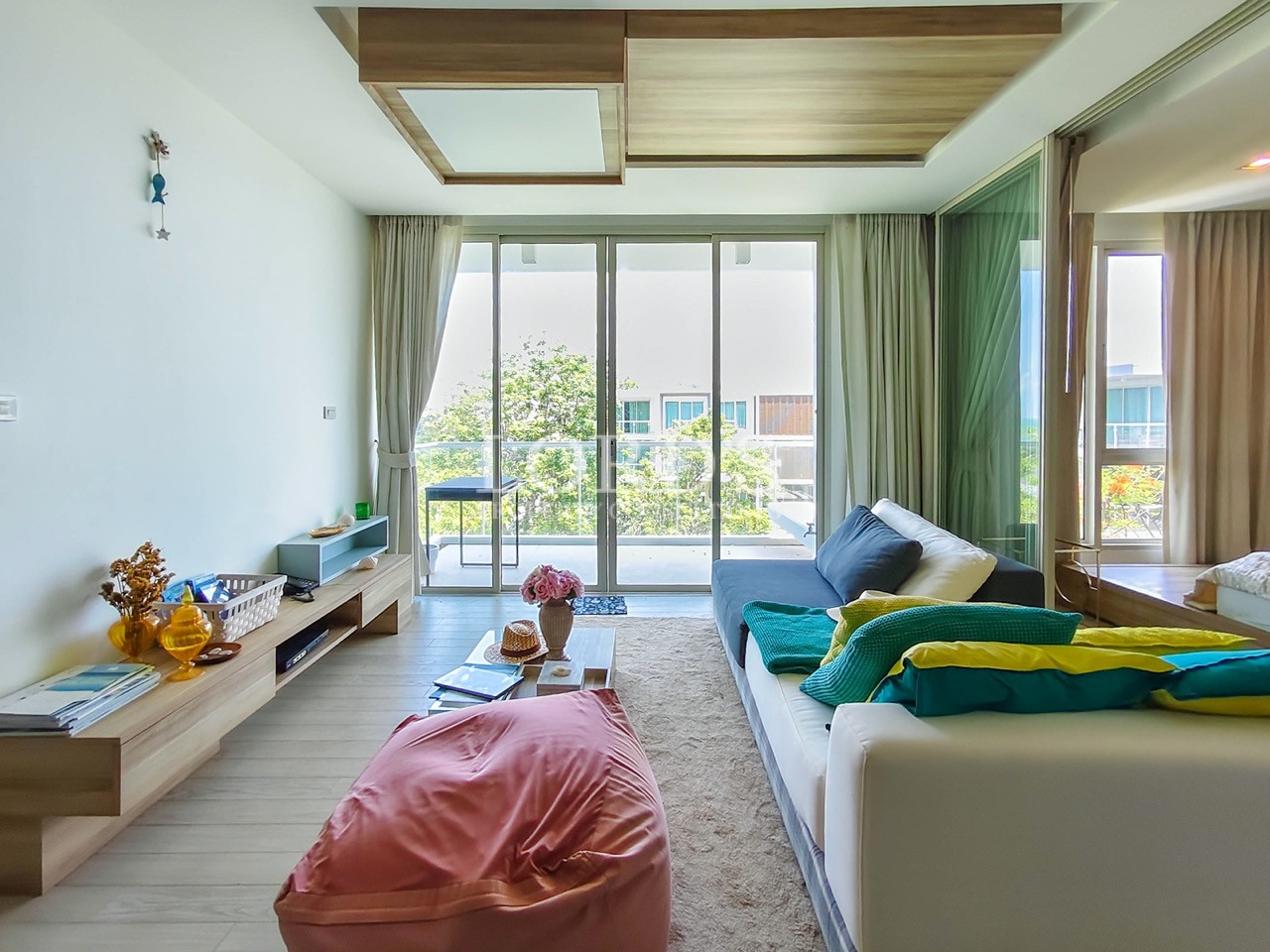 Modern apartment living room with large windows, comfortable seating, balcony access, and contemporary interior design