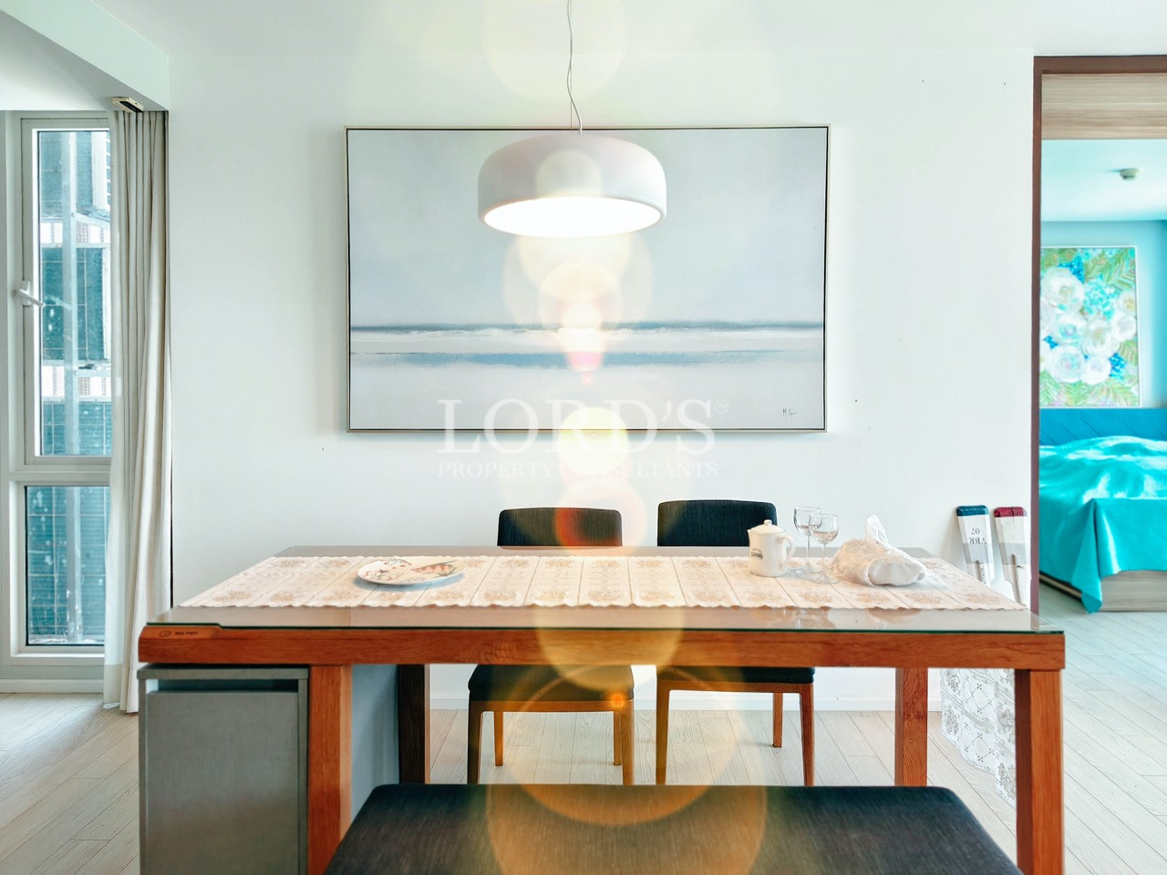 Modern apartment dining area with wooden dining table, contemporary lighting, and open-plan interior design
