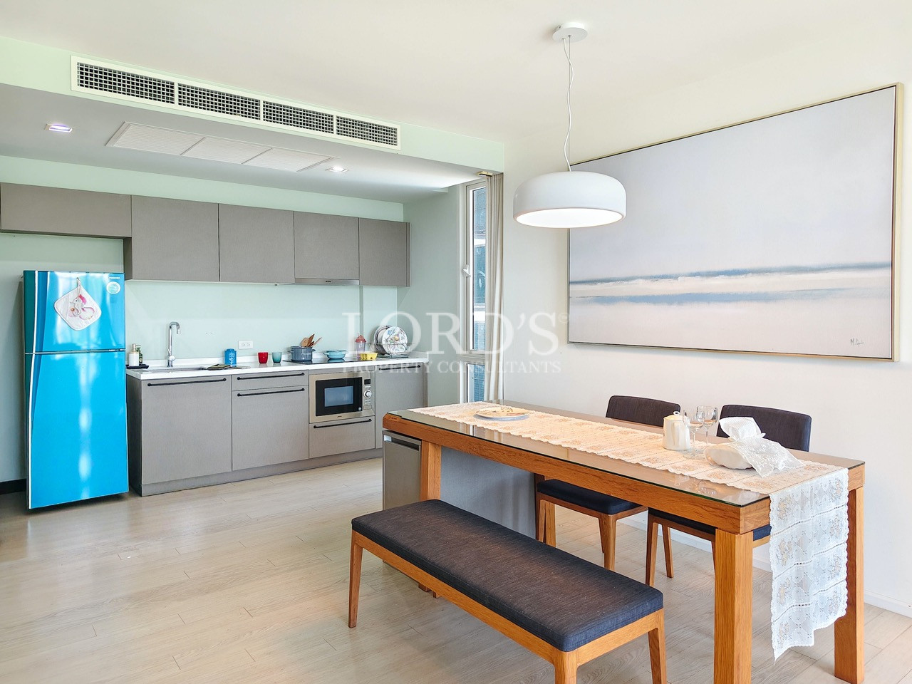 Modern apartment kitchen and dining area with contemporary cabinetry, built-in appliances, and minimalist interior design