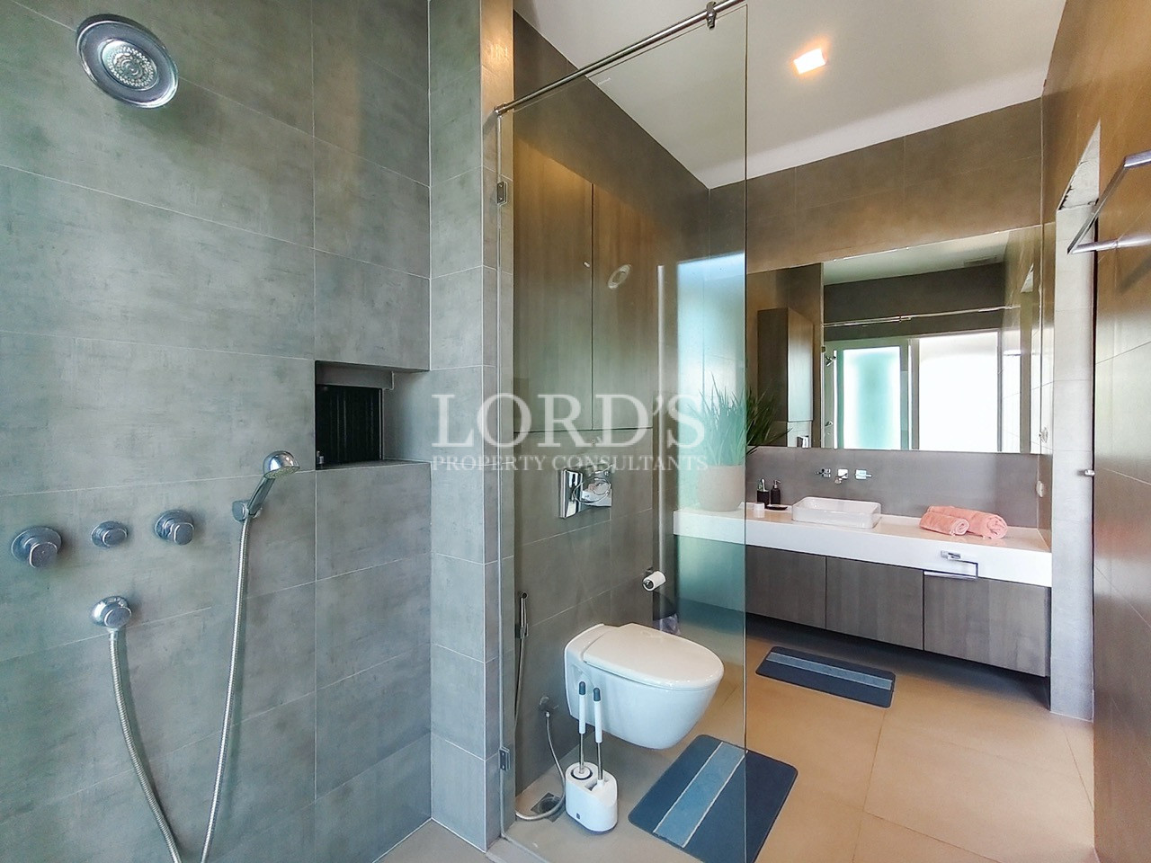 Luxury modern bathroom with rain shower, frameless glass enclosure, floating vanity, and contemporary tile design