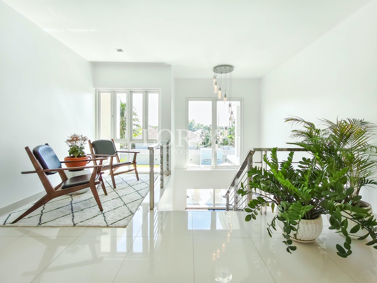 Luxury upstairs lounge with modern seating, indoor plants, staircase, and large windows with natural light