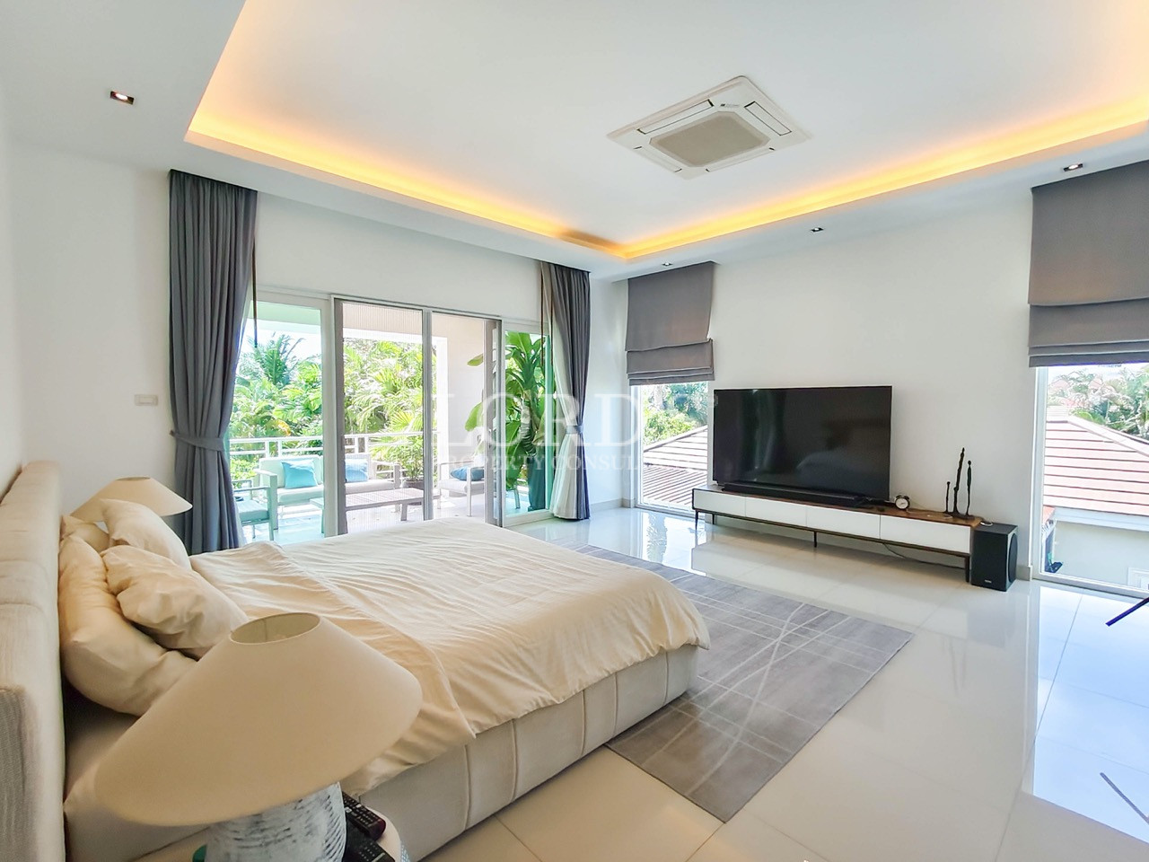Luxury master bedroom with king-size bed, private balcony, large TV, and modern minimalist interior