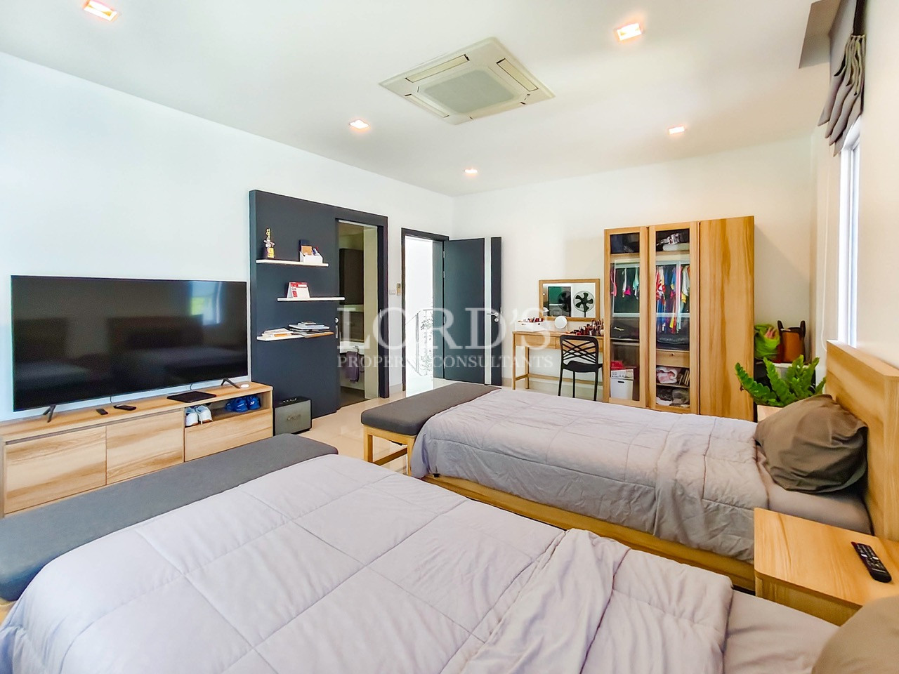 Modern twin bedroom with two single beds, TV unit, wardrobe, study desk, and contemporary interior