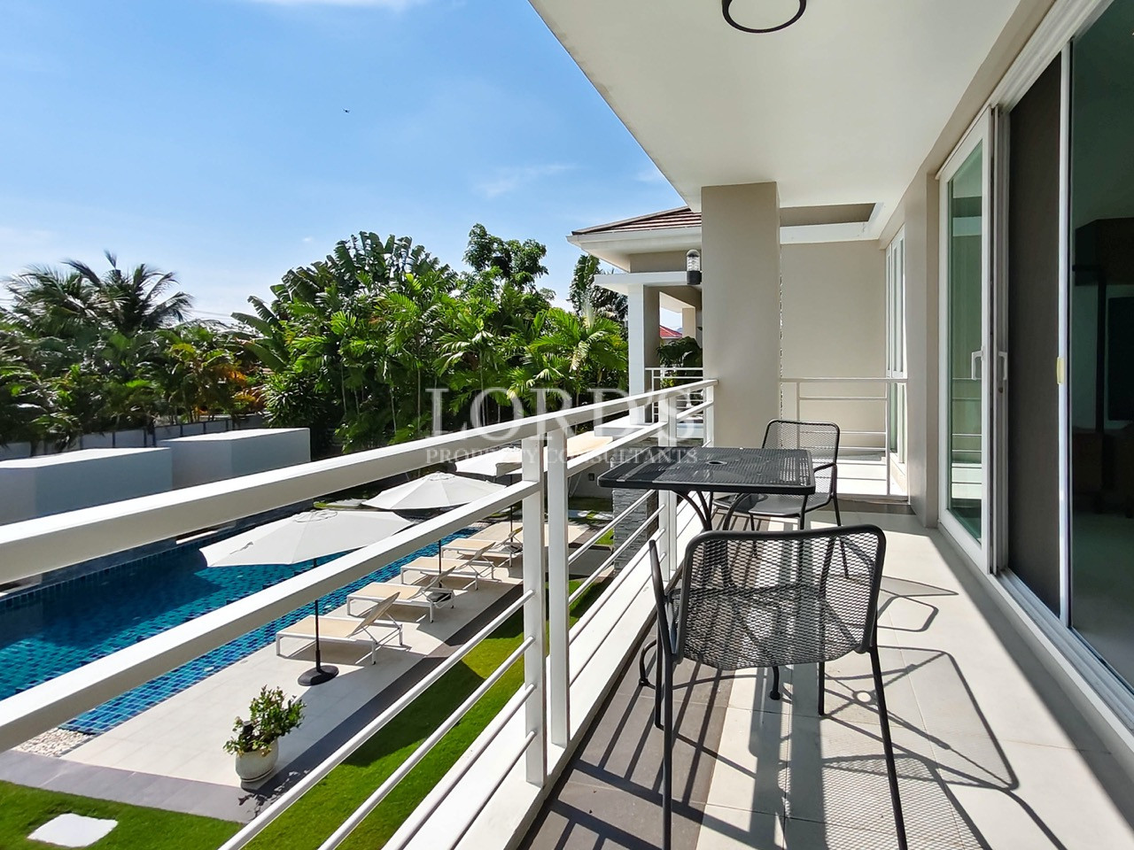 Luxury villa balcony overlooking private swimming pool, landscaped garden, and tropical surroundings