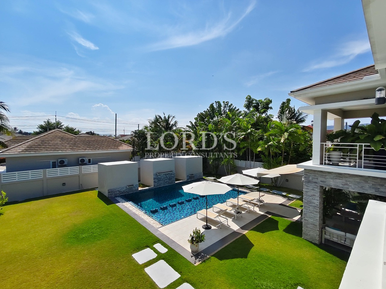 Luxury villa with private swimming pool, landscaped garden, sun loungers, and tropical outdoor living area
