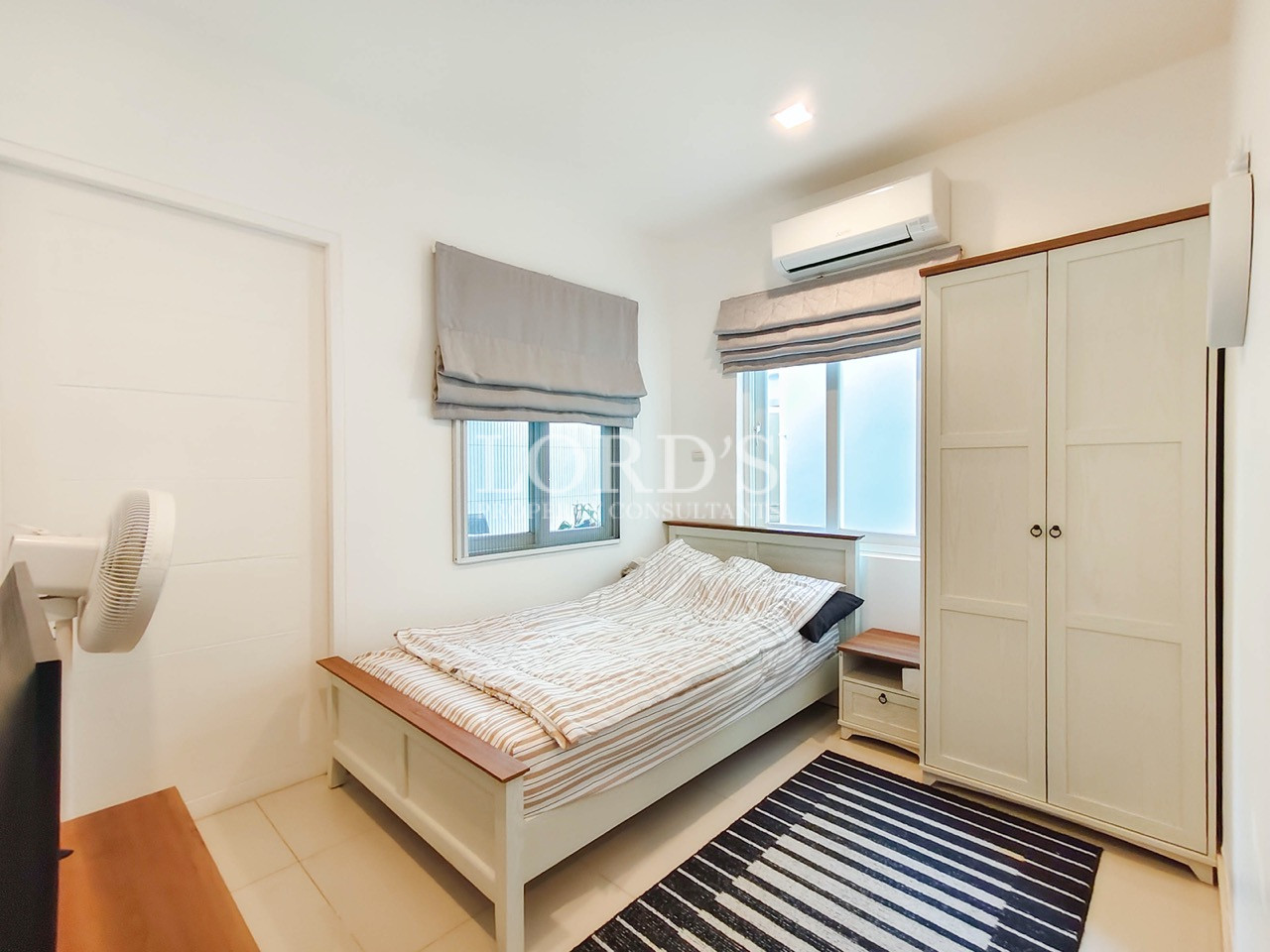 Modern luxury bedroom with queen bed, wardrobe, air conditioner, and natural light