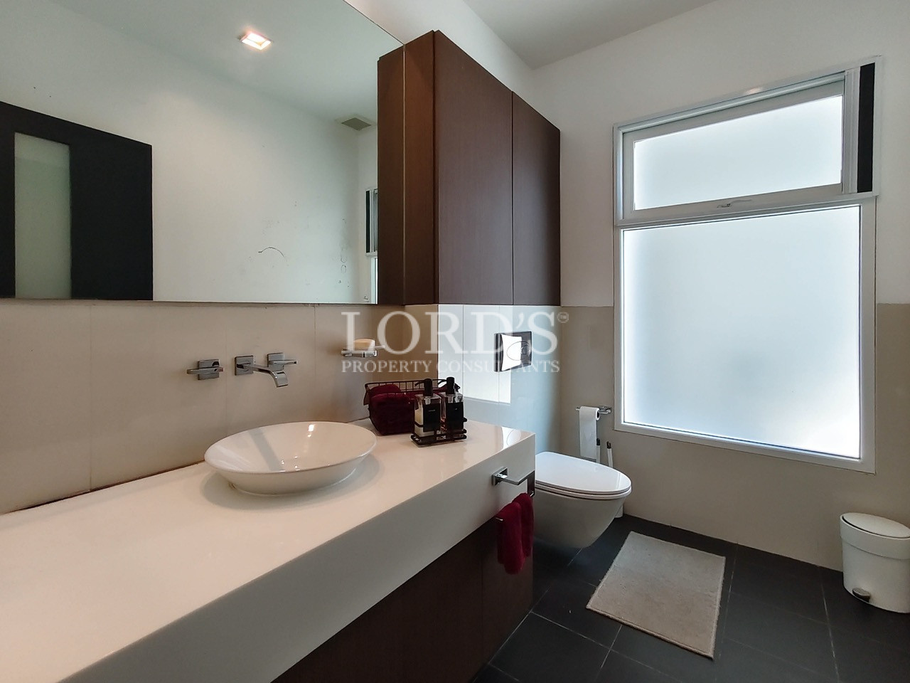 Modern luxury bathroom with floating vanity, vessel sink, wall-mounted toilet, and frosted window