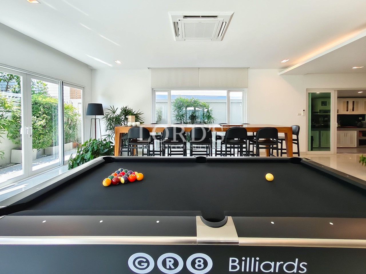 Luxury entertainment room with billiards table, dining area, and floor-to-ceiling glass doors