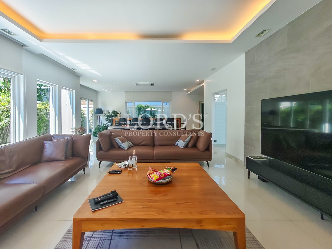 Luxury modern living room with leather sofas, wooden coffee table, large TV, and open-plan interior