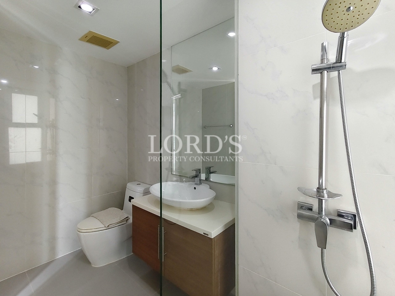 Modern bathroom with a glass shower enclosure, vanity, mirror, and white marble-style tiles